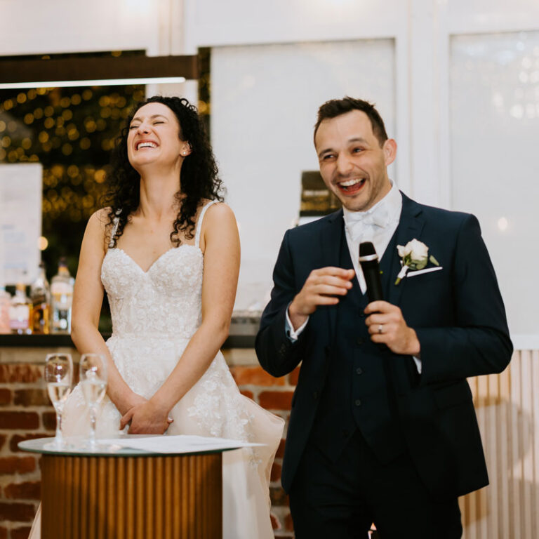 Bride and groom laughing while presenting my speech
